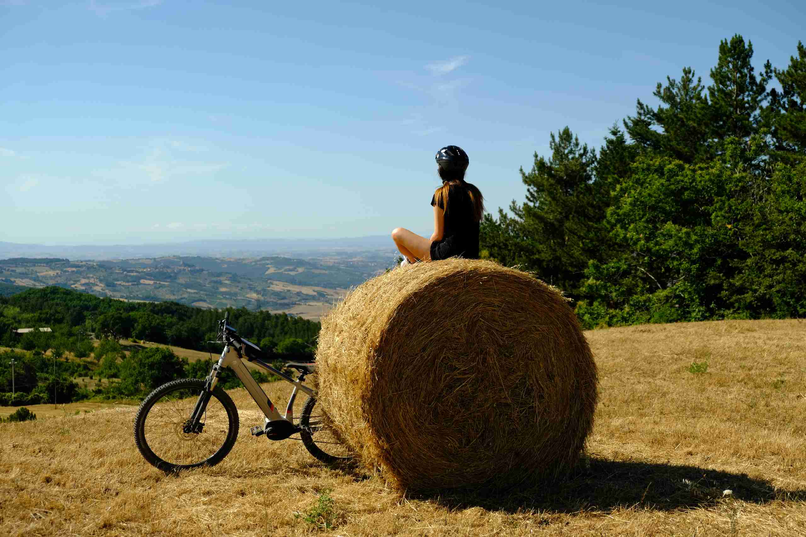 Una ragazza che si è fermata durante un tour in e-bike a fare una foto su una rotoballa